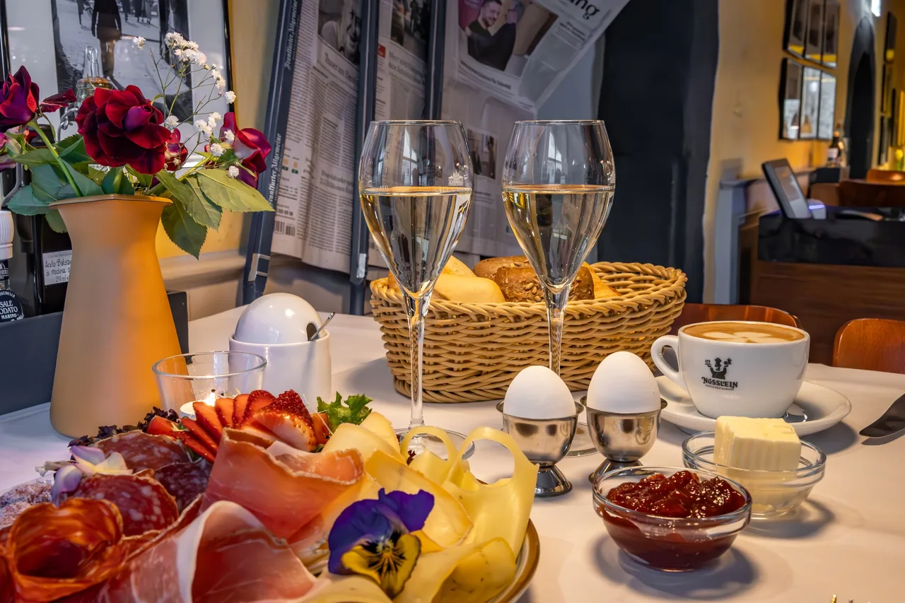 Gedeckter Frühstückstisch mit Aufschnitt, Käse, Eiern, Brötchenkorb, Cappuccino und Sekt im Café Nüsslein Erfurt